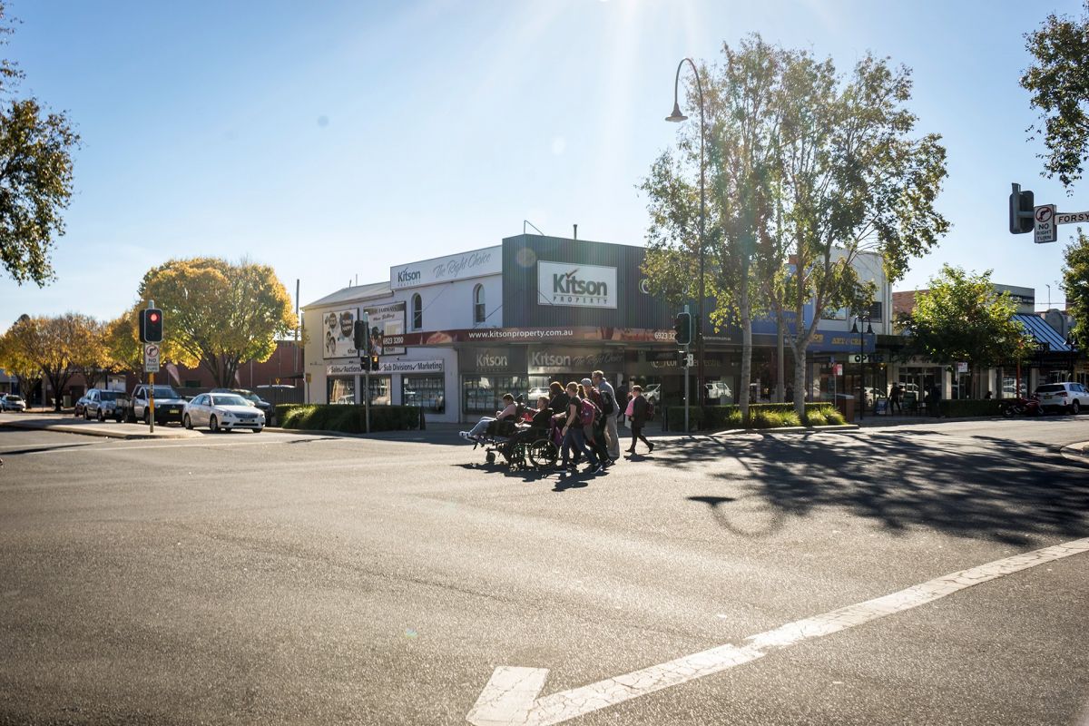 People on foot and in wheelchairs crossing road at intersection 