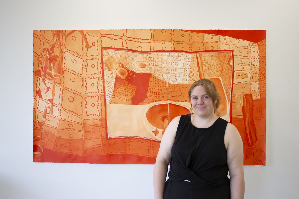 Young woman stands in front of a large artwork