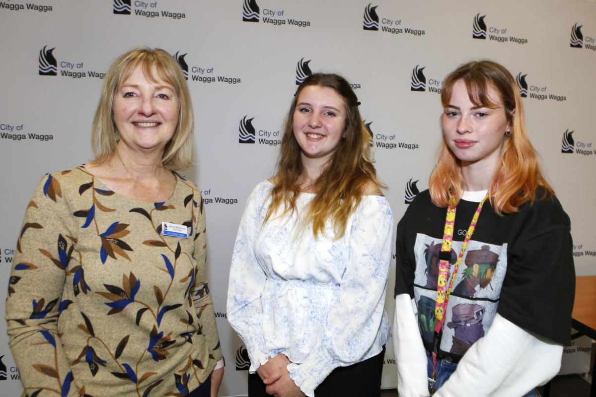 Mature woman and two young women standing in front of city logo banner