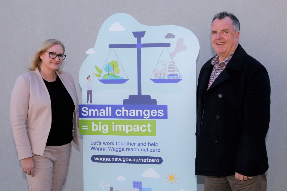 Strategic Sustainability Advisor Carly Hood and Mayor Councillor Dallas Tout standing with Net Zero Emissions display sign. 
