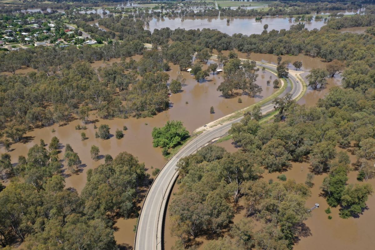 Drone image showing a bridge with flood water on both sides where parkland was originally.