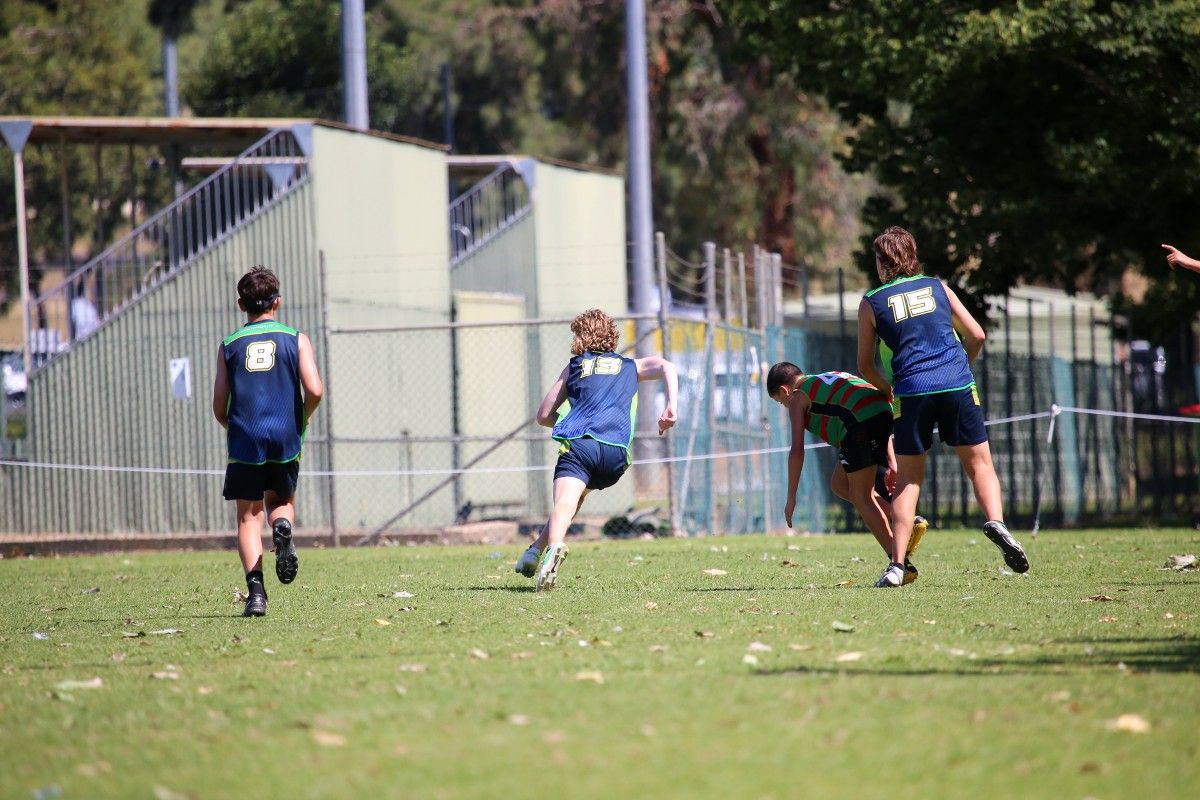 Back view of four junior touch football players in action on the pitch.