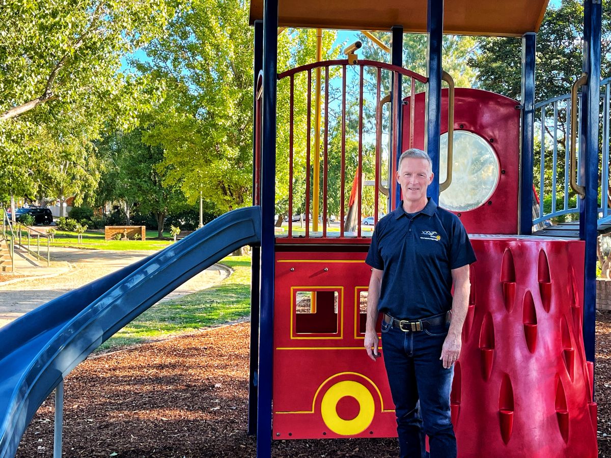 Man representing local Rotary branch, standing beside playground equipment to be upgraded