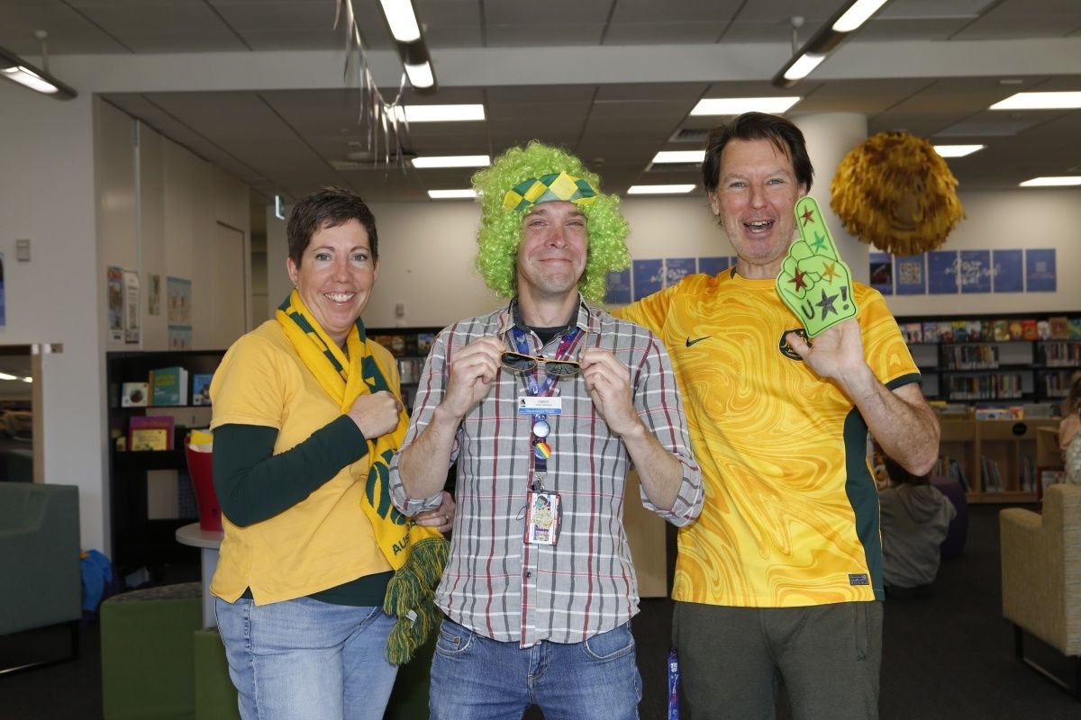 Three library staff dressed up for Storytime at the library on Green & Gold Day