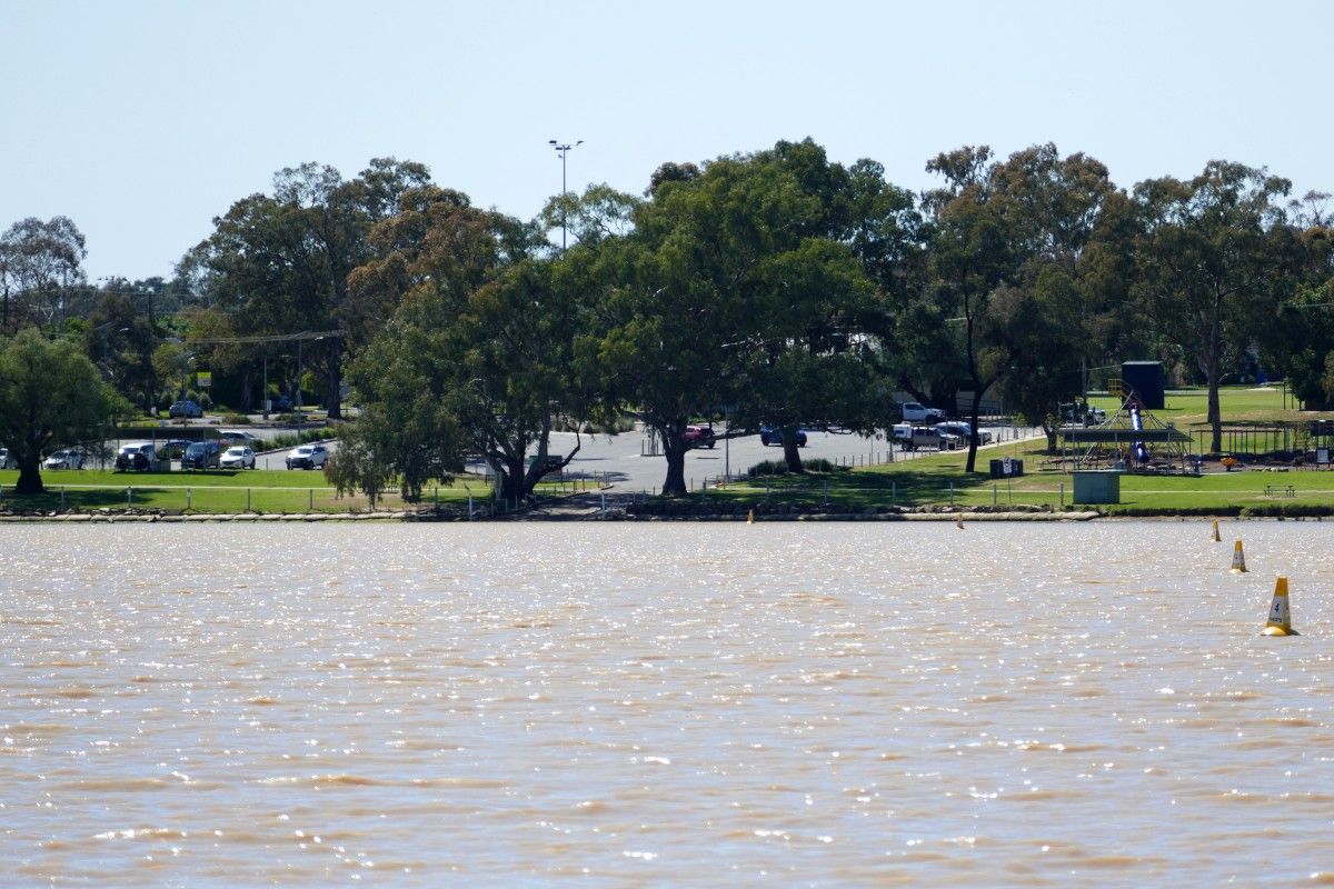 Lake in the foreground, with foreshore, boat ramp and carpark in the background, on a sunny day.