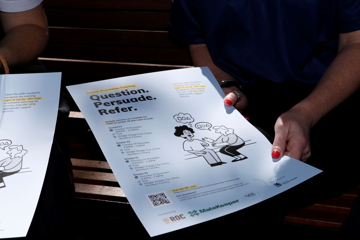 Close up of hands holding an informative sign about Suicide Prevention training.