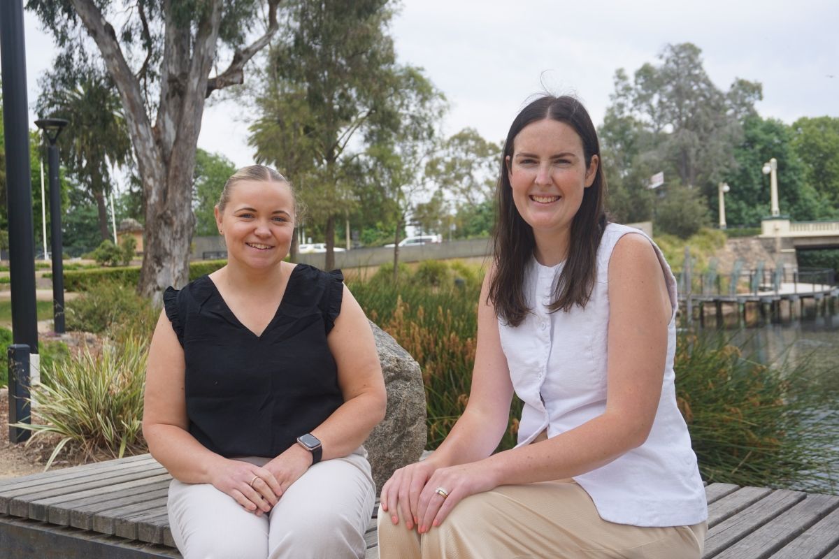 Wagga Wagga Council Event Officers Amy McDonnell and Emma Corbett  seated in front of Wollundry Lagoon