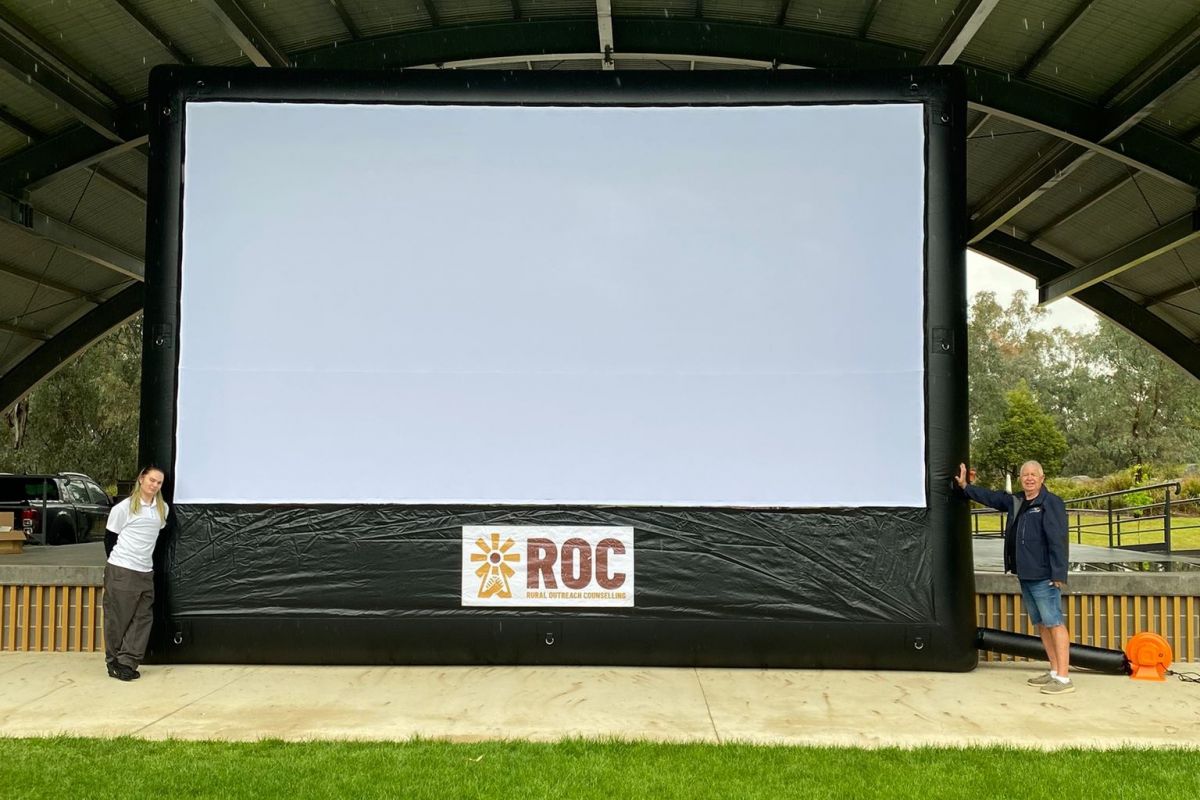 Large blow-up movie screen, with a woman and man standing on either side of it.