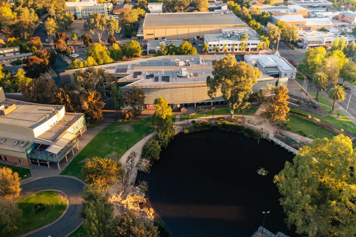 Aerial view of lagoon and glass and steel building in a city centre.