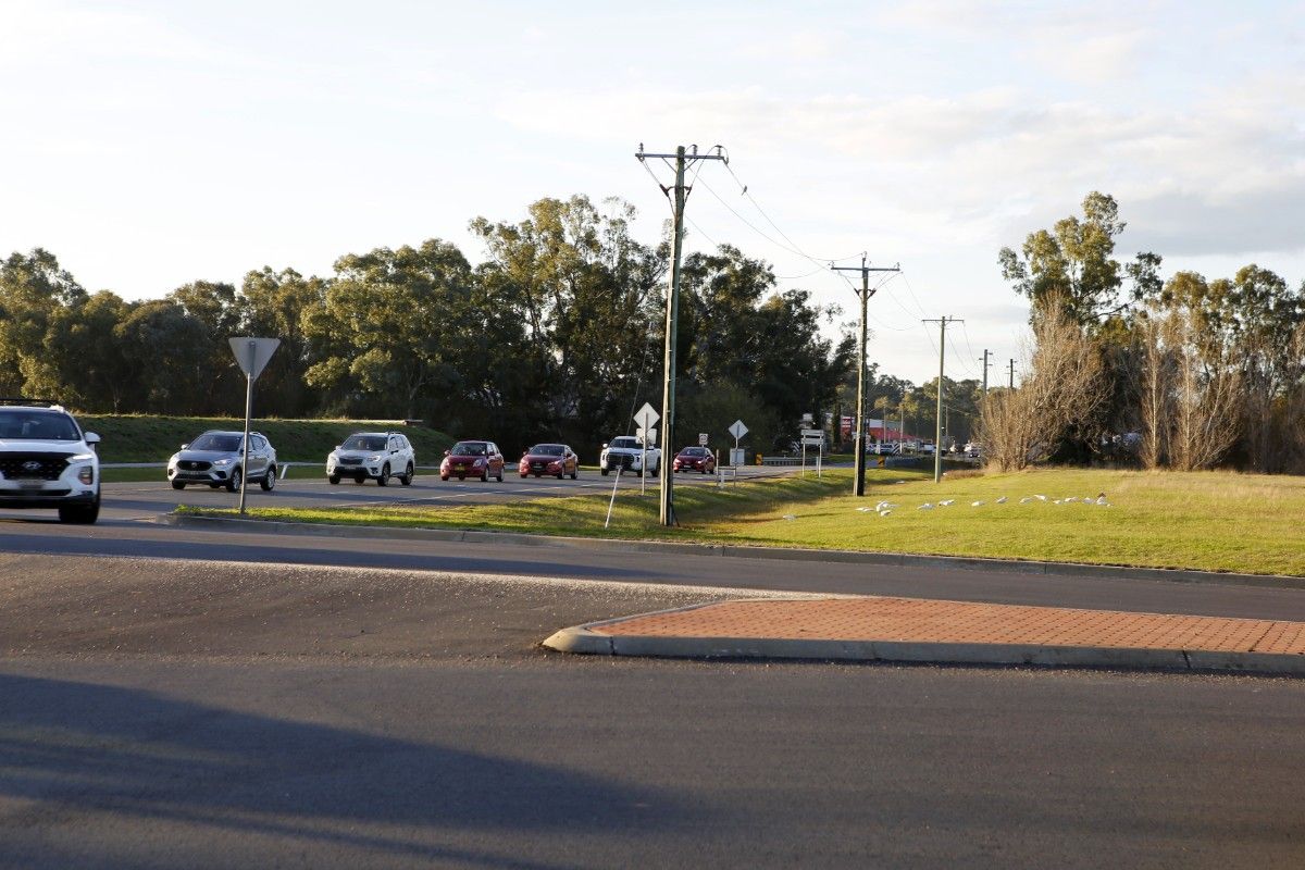 A line of vehicle traffic along a road approaching a roundabout.