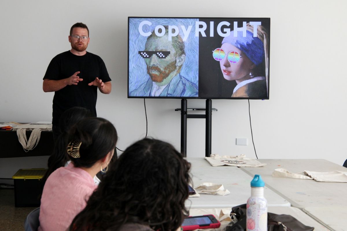 A man stands at the front of a room giving a presentation.