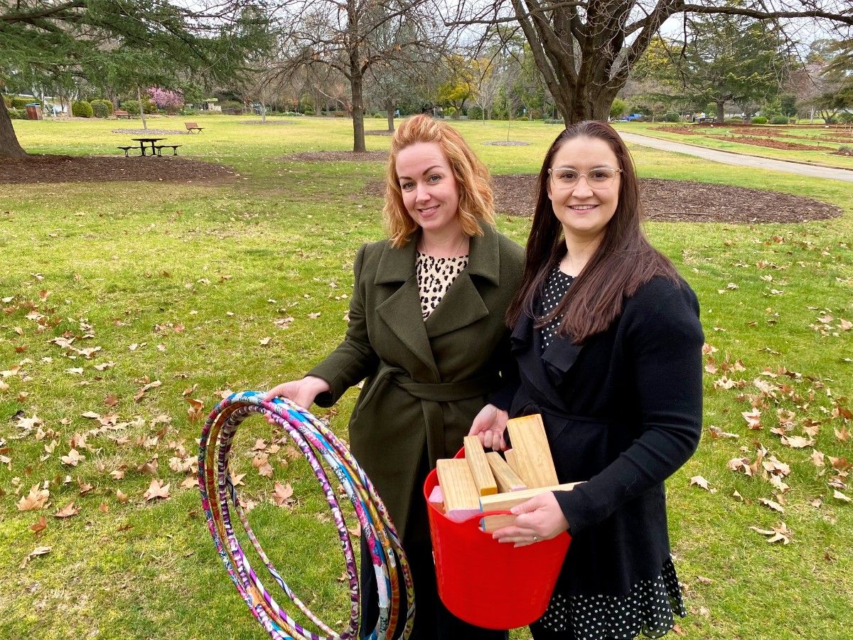 Women holding hoops and wooden blocks, standing in garden