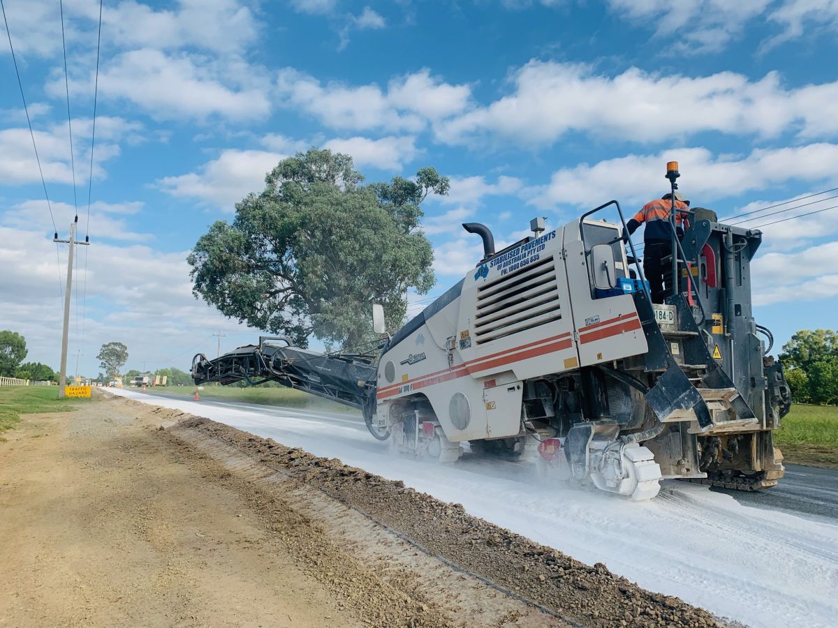 A large truck spreading white powder onto a road