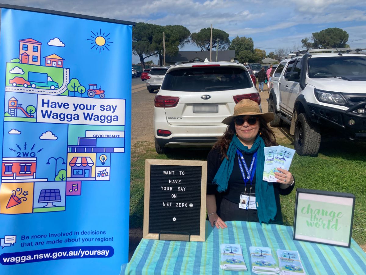 Council NZE officer sitting at a booth at the River and Wren Markets with WWCC Have your say branding adorning the table. 