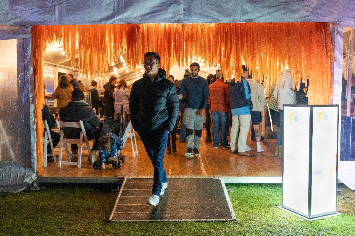 Man walking out of marquee with other people inside marquee standing at tables