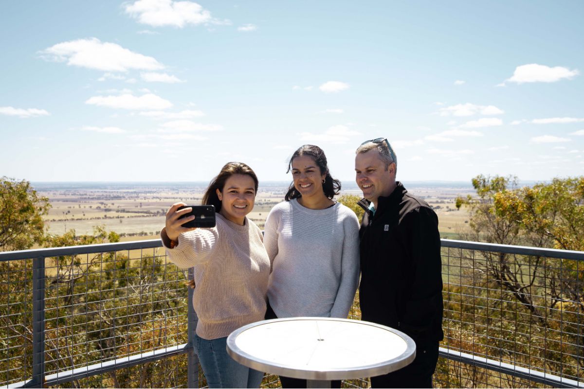 Two women and one man take a selfie at a scenic lookout.