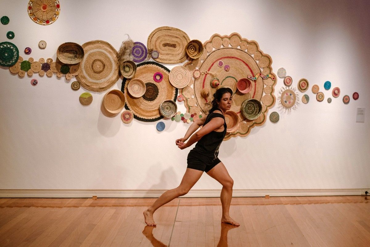 Woman dancing in front of installation on wall at art gallery