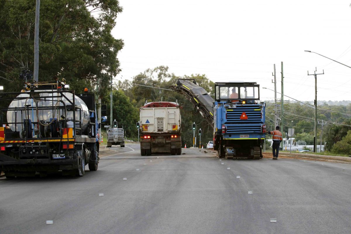 A group of trucks on a newly resurfaced road.