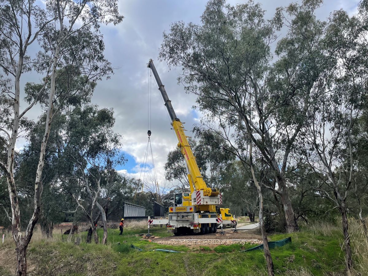Crane and workers preparing to install bridge over Marshalls Creek in bushland