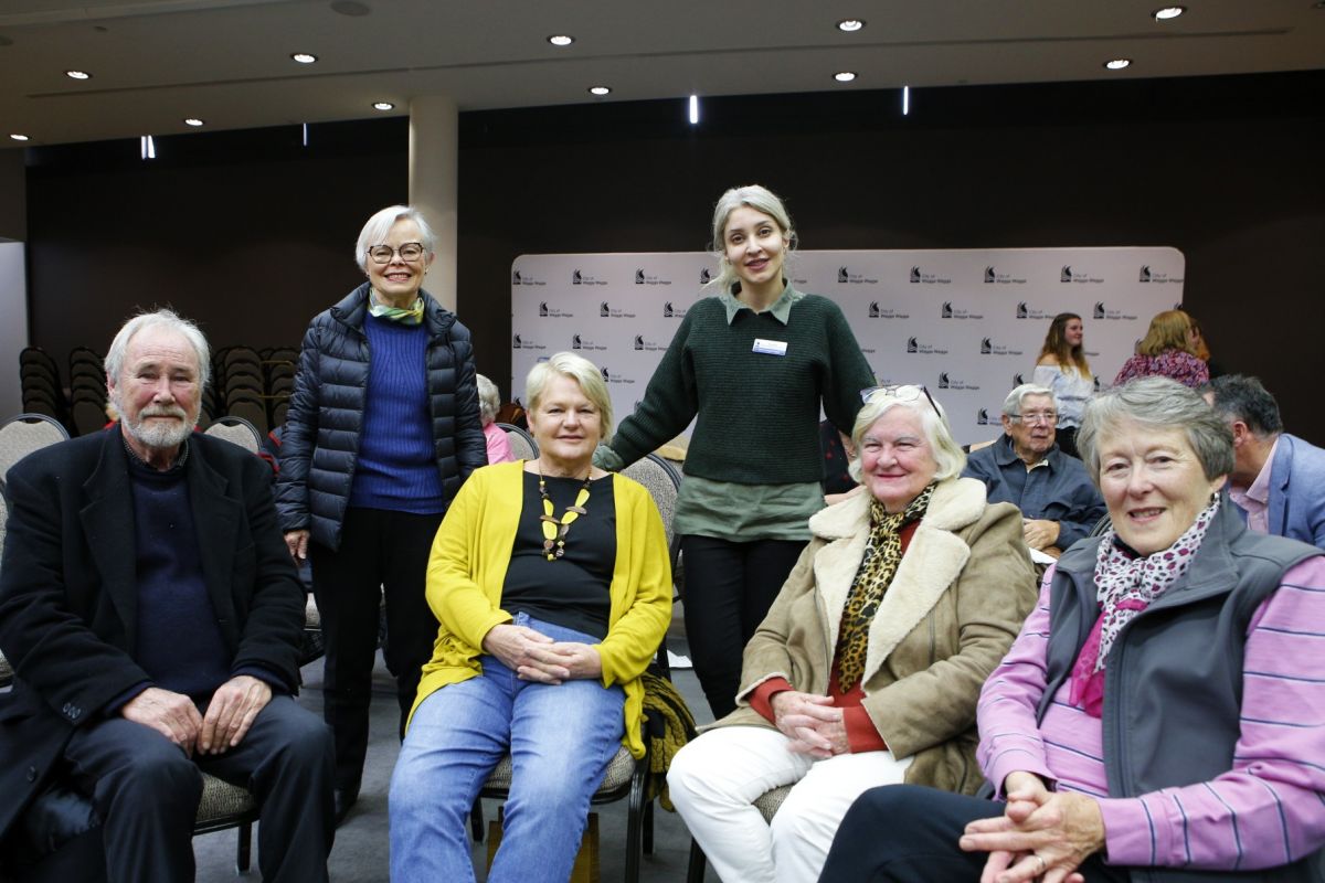 Man and five women siting and standing in council chambers