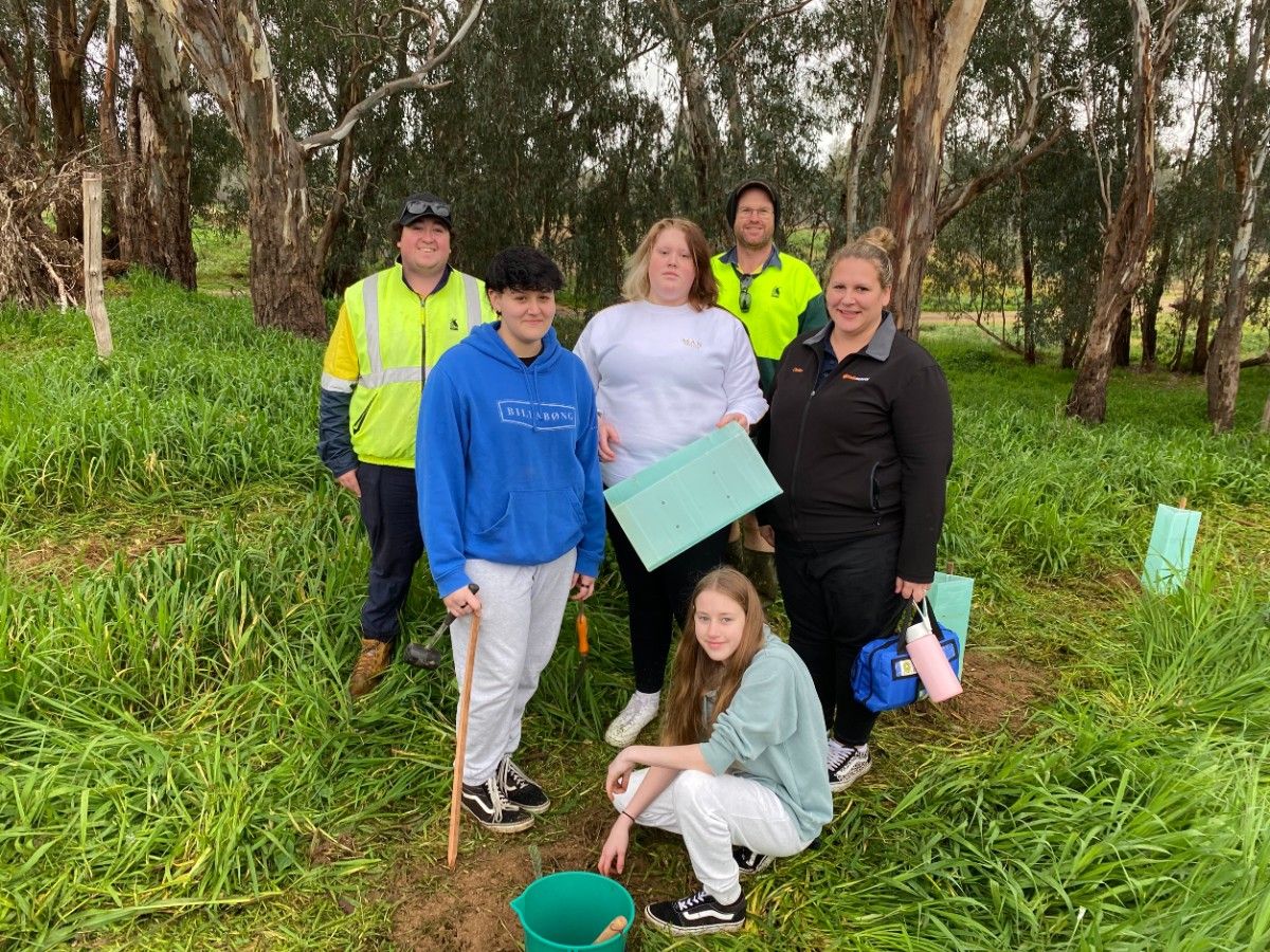 A group of people standing in a bushland setting