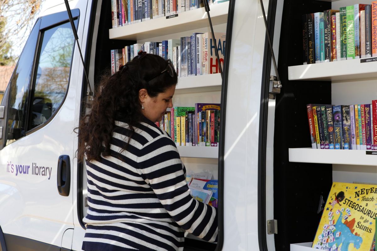 Female library officer stocking shelves of Agile Library van