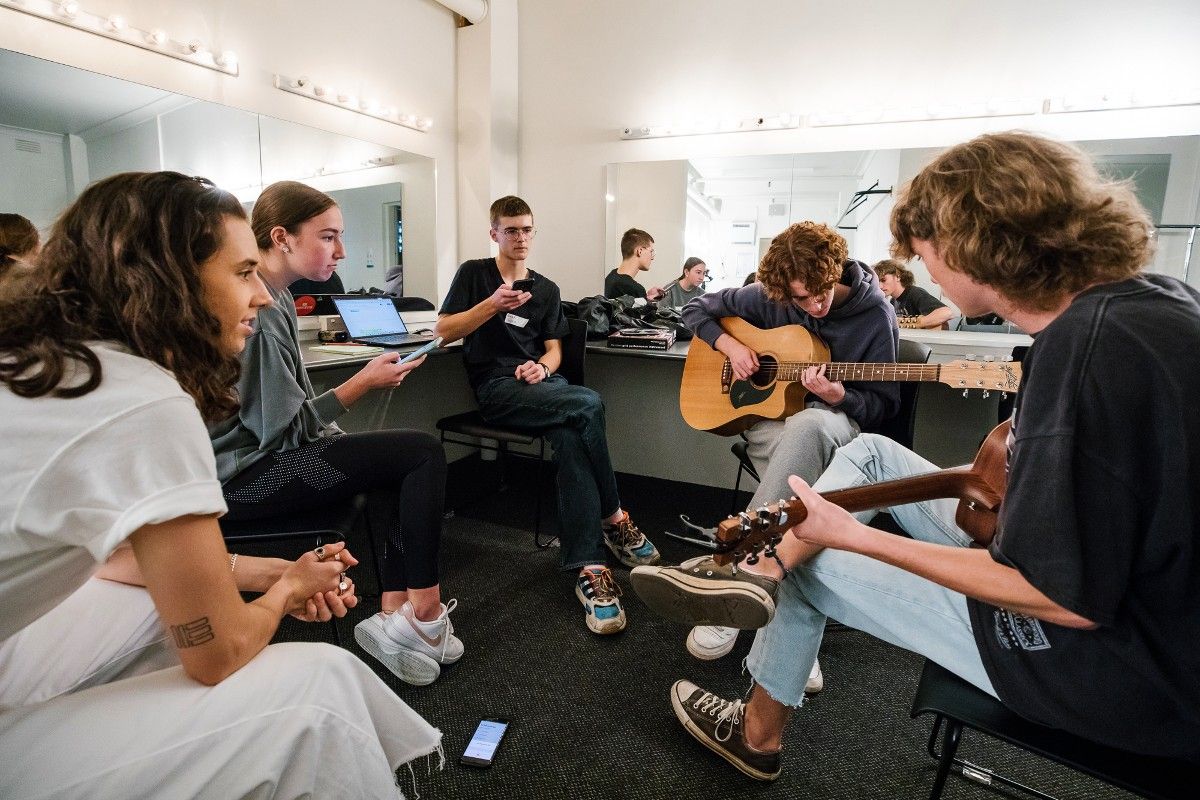 Two female and three male budding young musicians with mentor, two playing guitar