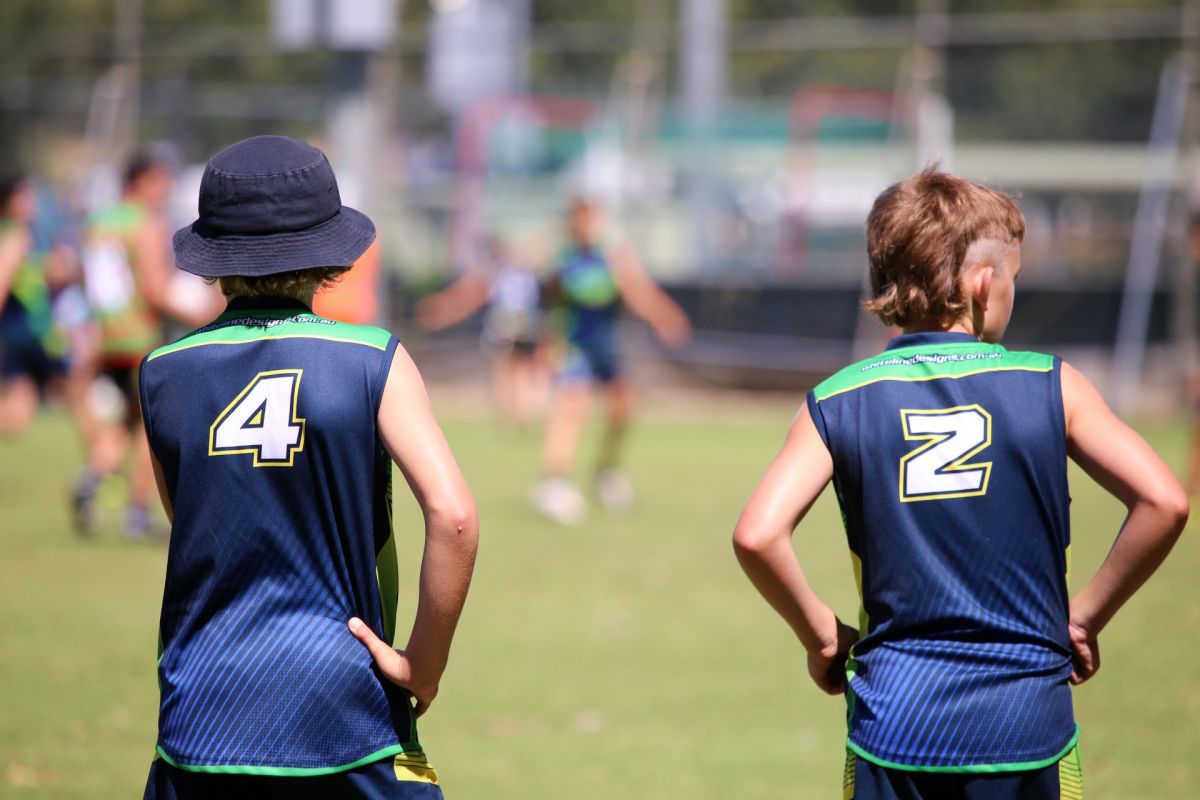 Back view of two junior touch players on sidelines