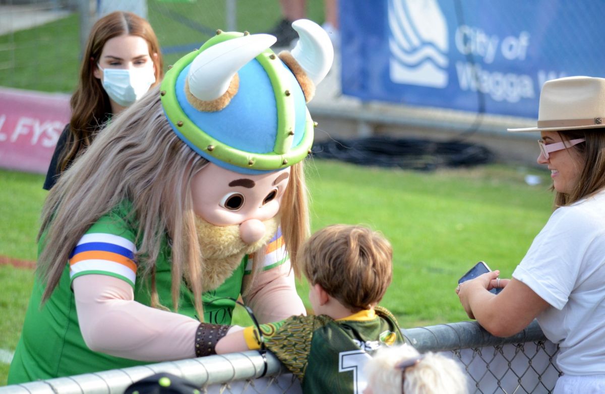 Raiders mascot interacting with young fan on sidelines