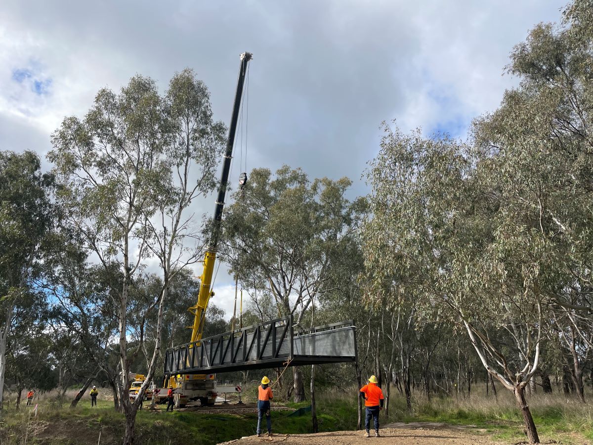 Crane and workers lowering a steel bridge over Marshalls Creek on ATP path at Koorginal
