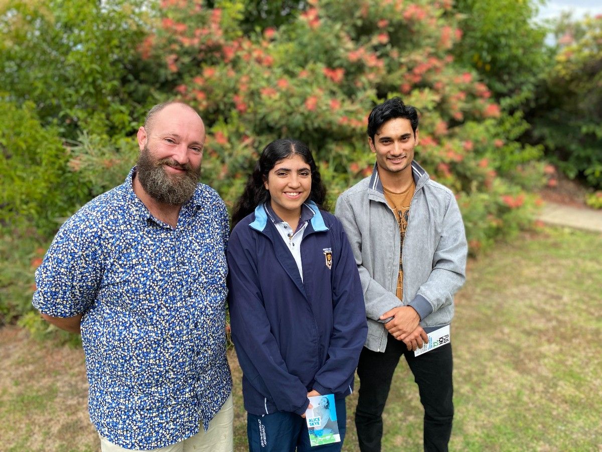 A man stands with a teenage girl and boy in a garden setting