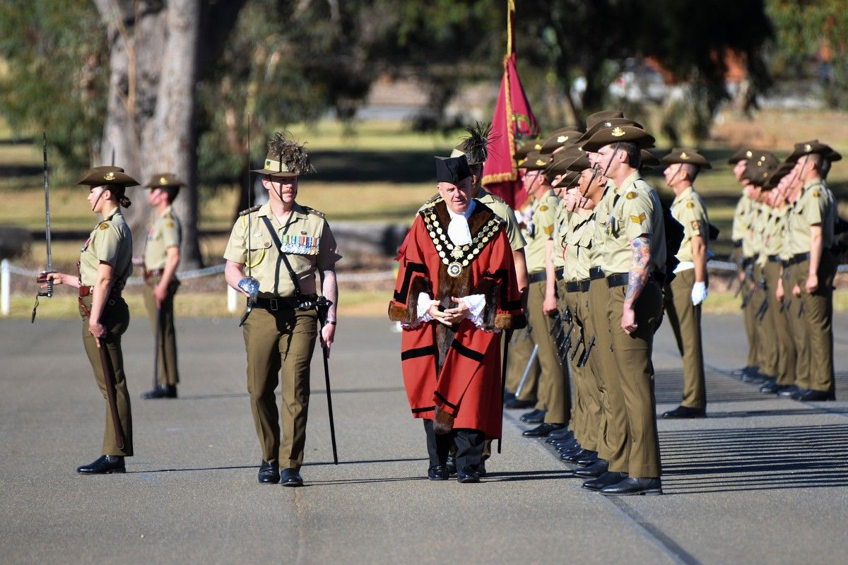 Soldiers on parade being inspected by man in mayoral robes