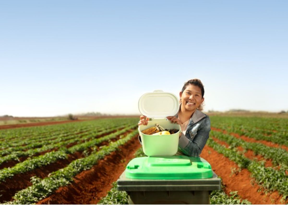 Woman holding FOGO bin in paddock