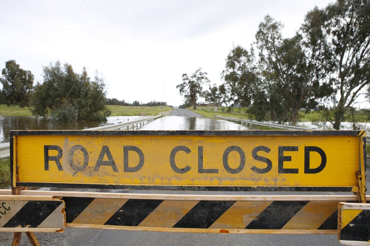 Road closed sign in foreground with flooded road in background