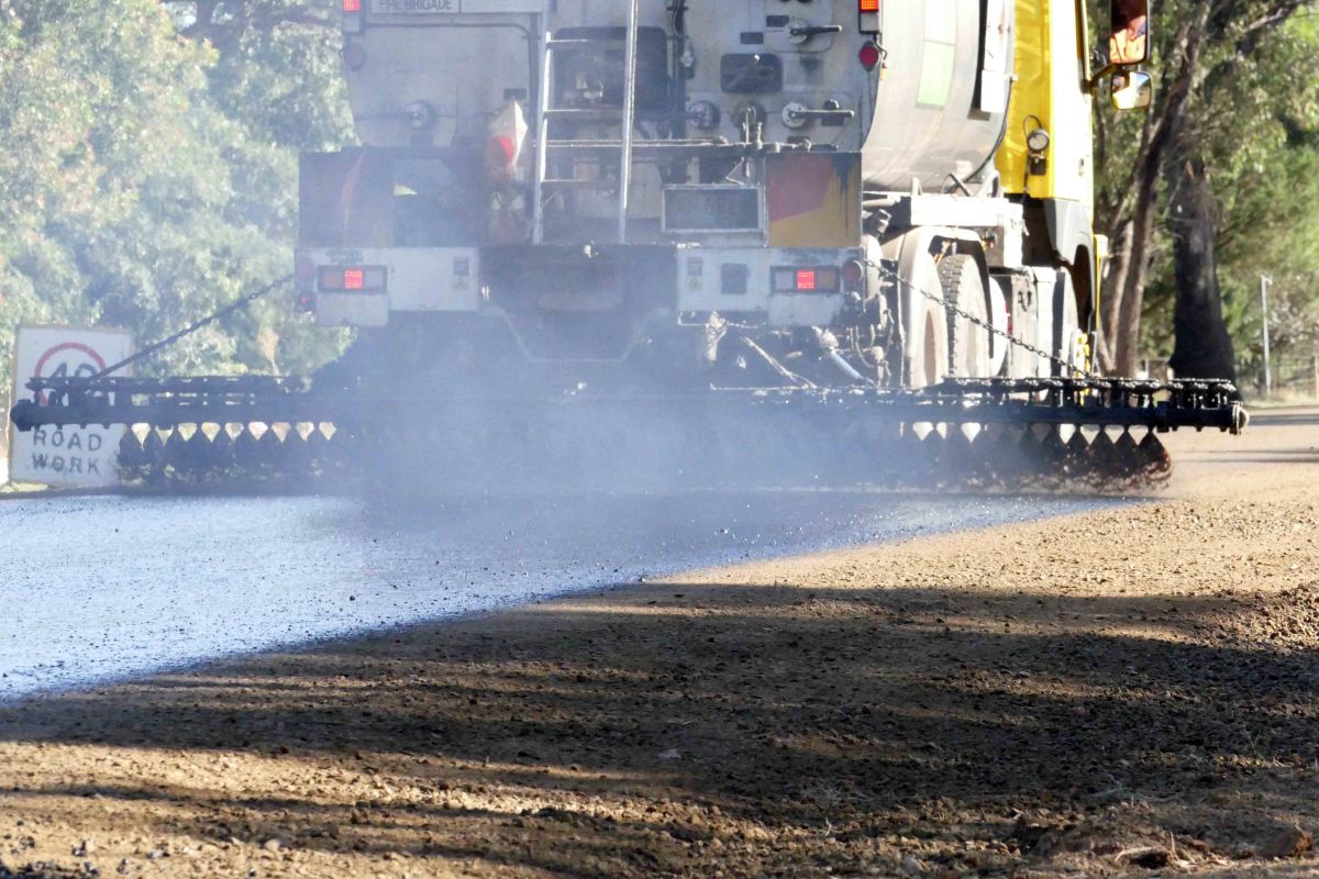 Bitumen seal being sprayed on road from truck