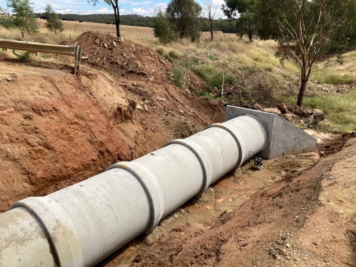 An enormous concrete pipe laying in the ground