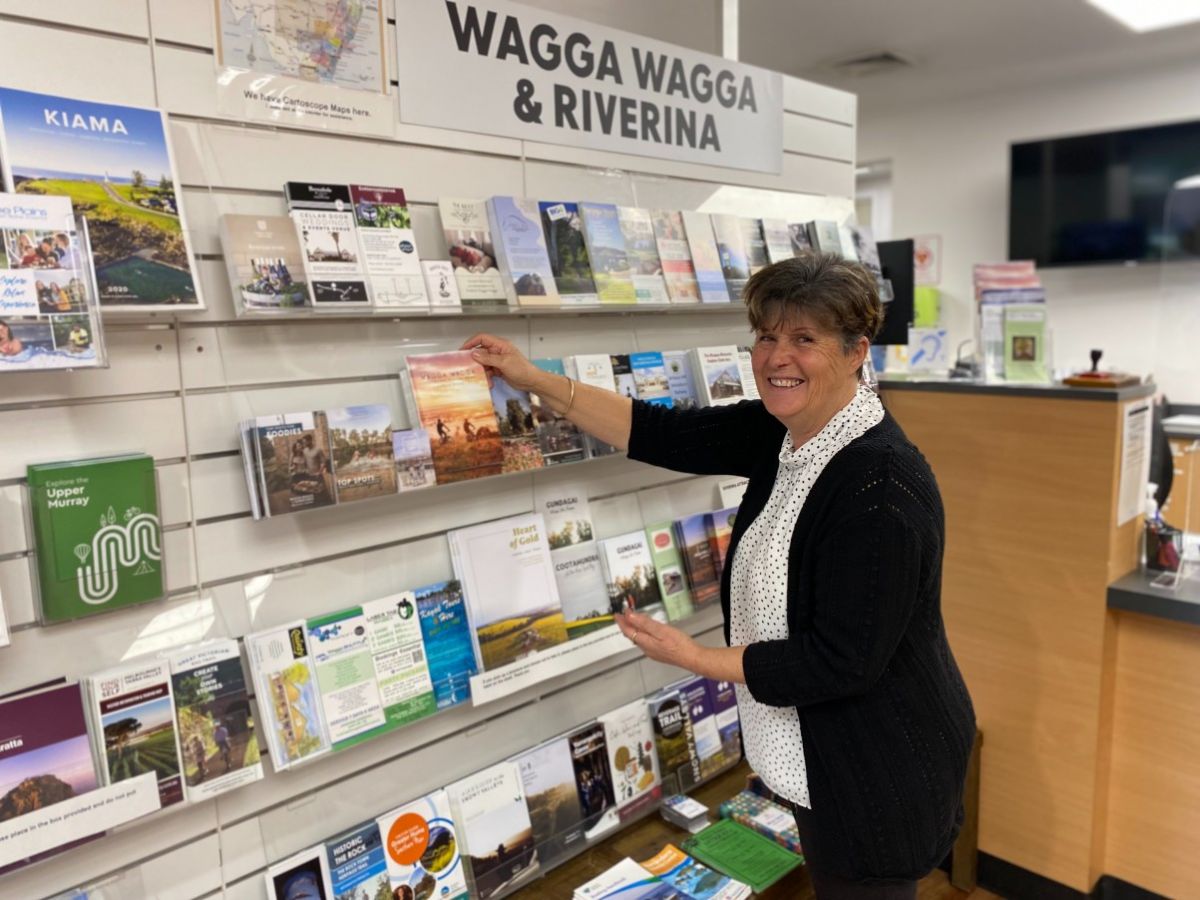 Smiling woman reaches to pick up a map