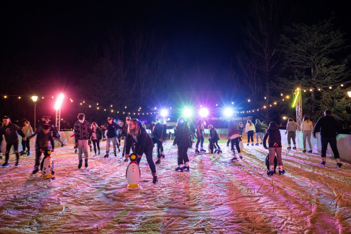 People skating on an outdoor ice rink during the evening.