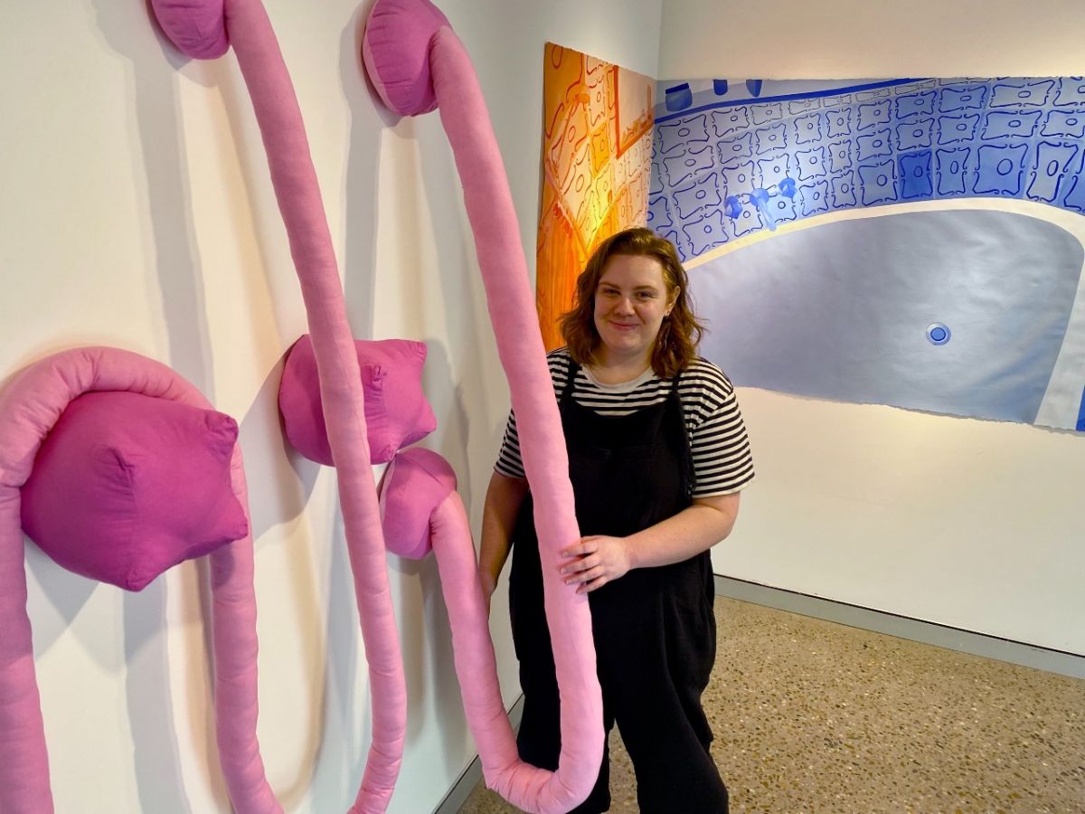 A young woman standing beside a three dimensional artwork