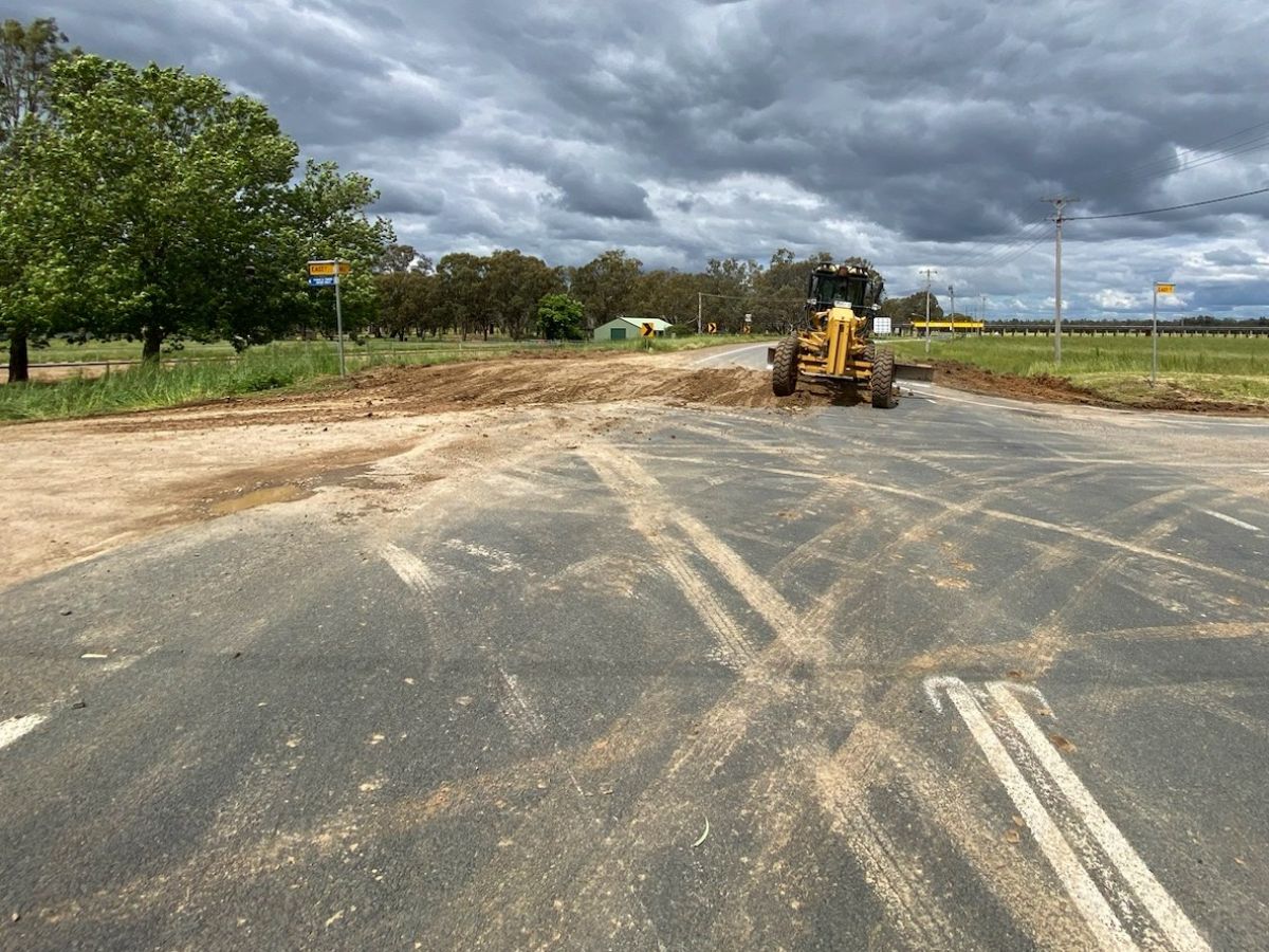 A grader constructs a dirt levee across a road.