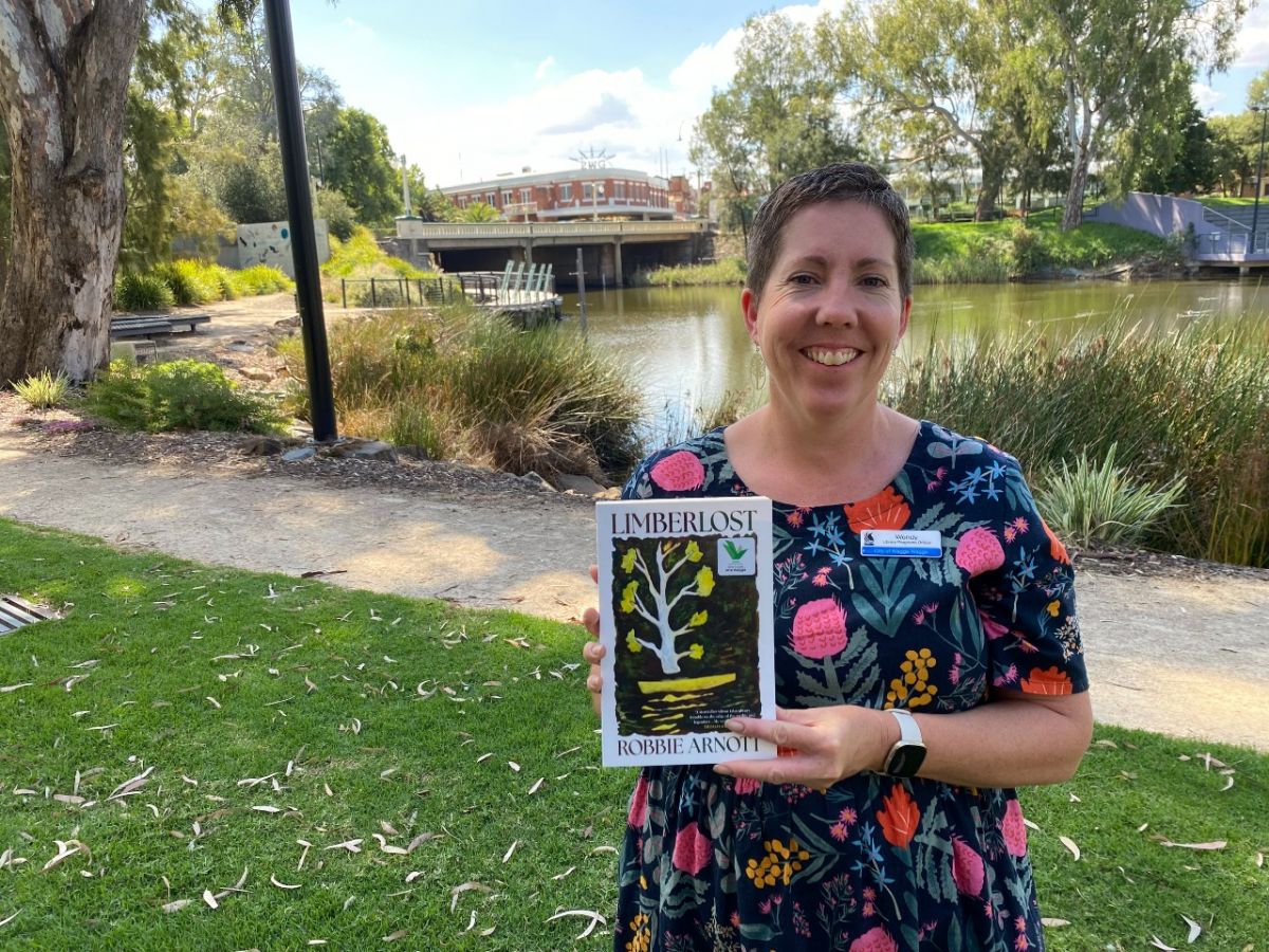 A woman standing in a park holding a book