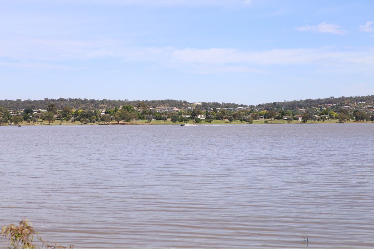 Daytime photo of Lake Albert with jetski being ridden in the distance and houses on the far bank visitle