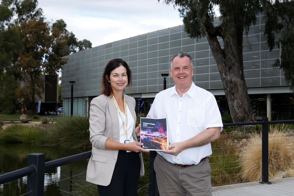 A woman and man stand outside the Council building holding the published CSP document.