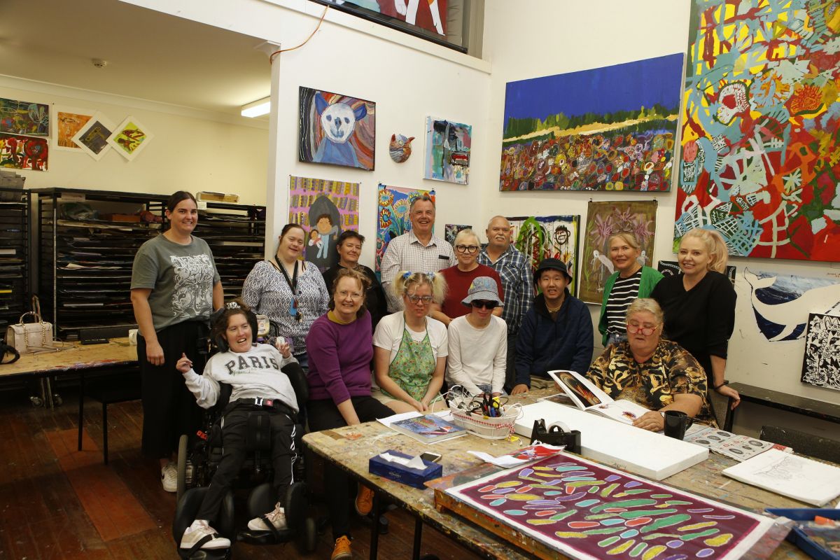 A group of people in an art studio having a photo with the Mayor. 