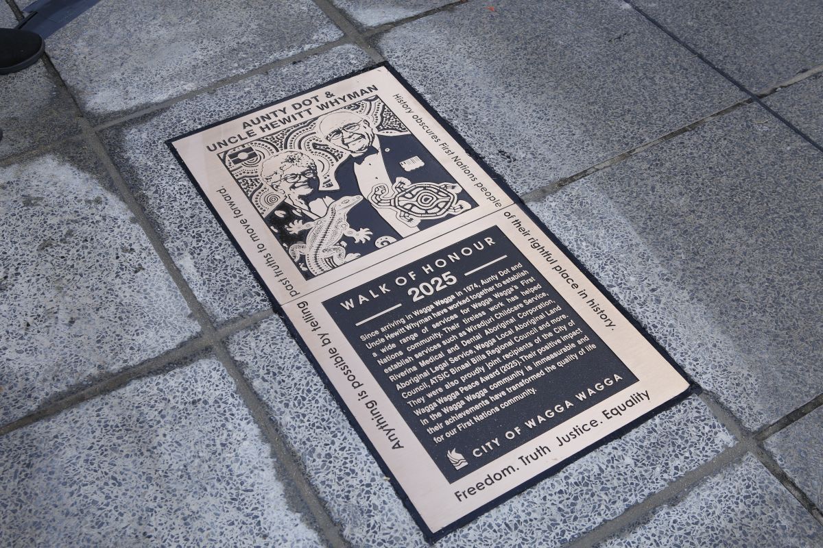 A close up of a bronze plaque set into a tiled pathway.