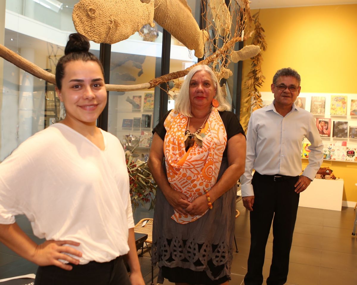 Two First Nations women and a man standing in front of art at gallery