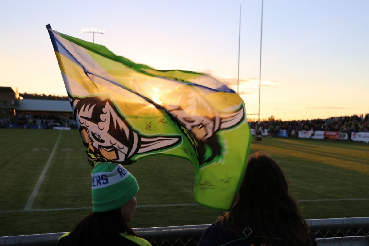 Two women holding Raiders NRL team flag 