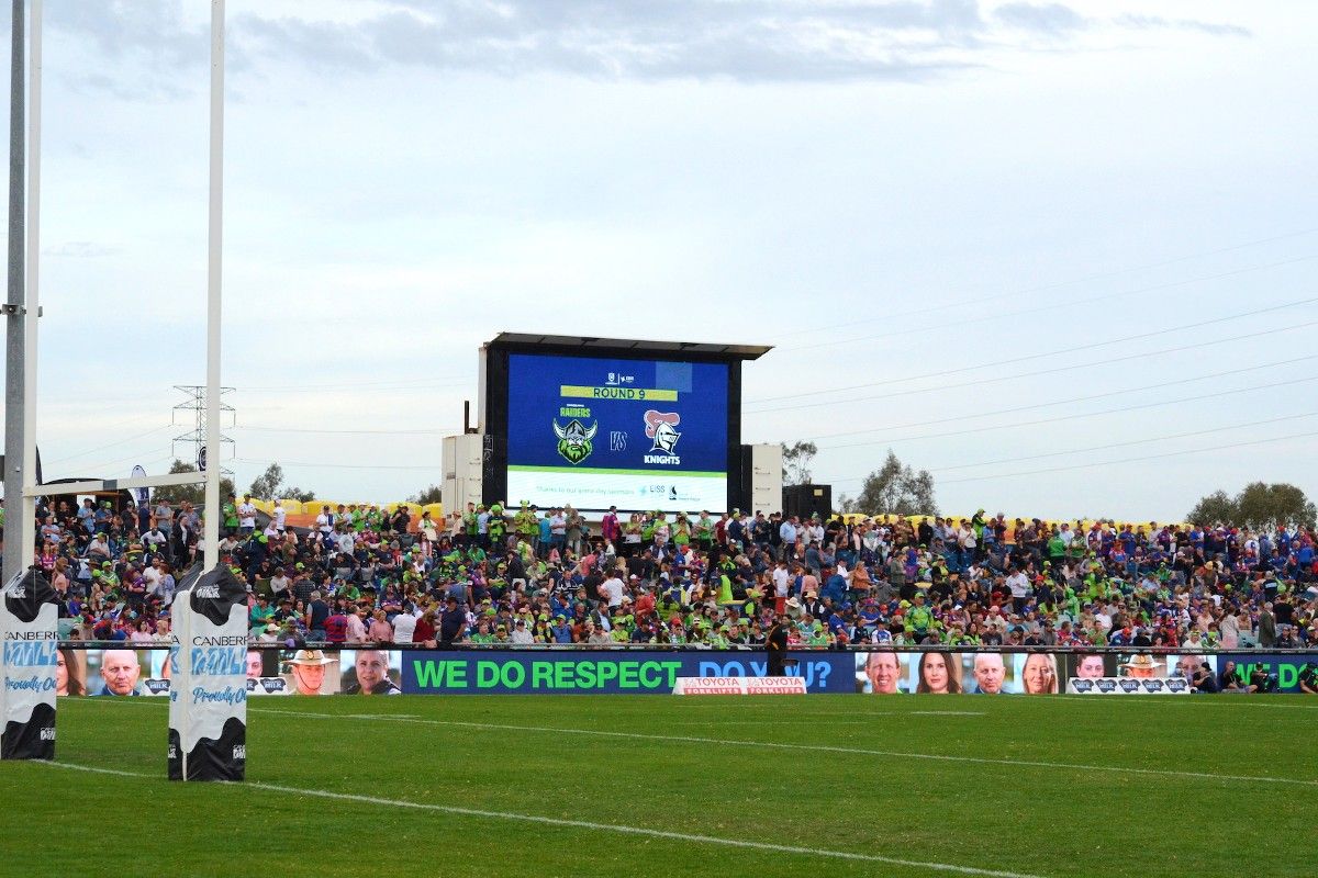 Crowd and score board in background with goal post in foreground