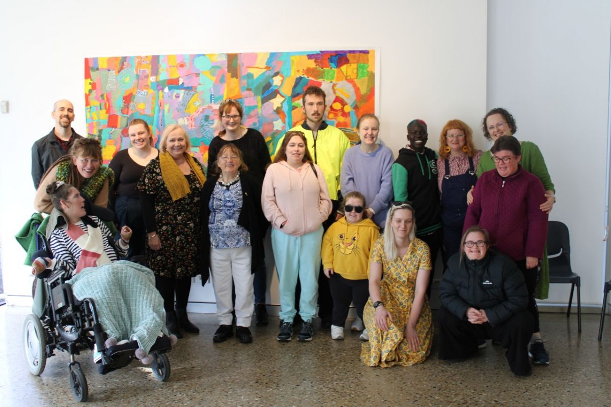 A group of people stand in front of a large artwork