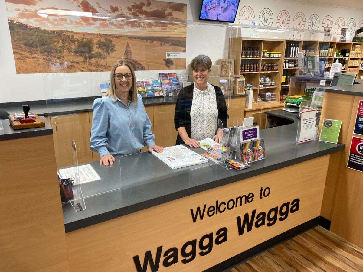 Two smiling woman stand behind a counter